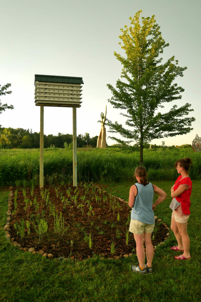 Two people look at the purple martin house and garden key at dusk.