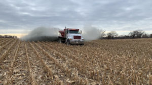 Truck spreading rock dust on a field